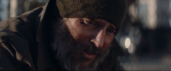Movie still from “Archenemy” (2020), directed by Adam Egypt Mortimer – A person with a beard wearing a hat; Close Up shot, Over the shoulder angle