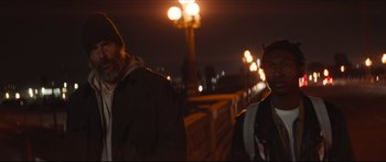 Movie still from “Archenemy” (2020), directed by Adam Egypt Mortimer – Two men standing next to each other on a bridge at night; Medium shot, Low angle