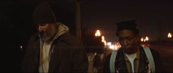 Movie still from “Archenemy” (2020), directed by Adam Egypt Mortimer – Two men standing next to each other on a street; Medium shot, Over the shoulder angle