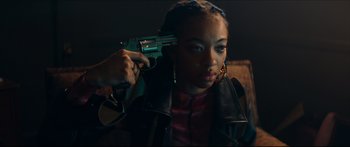 Movie still from “Archenemy” (2020), directed by Adam Egypt Mortimer – A woman holding a gun up to her face; Close Up shot, High angle