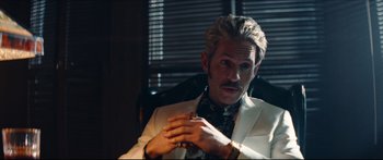 Movie still from “Archenemy” (2020), directed by Adam Egypt Mortimer – A man sitting in a chair wearing a white jacket; Close Up shot, Over the shoulder angle