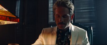 Movie still from “Archenemy” (2020), directed by Adam Egypt Mortimer – A person wearing a suit and tie; Close Up shot, Low angle