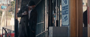 Movie still from “Archenemy” (2020), directed by Adam Egypt Mortimer – An older man walking down a street with a cane; Wide shot, Low angle