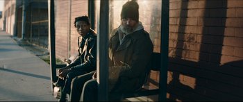 Movie still from “Archenemy” (2020), directed by Adam Egypt Mortimer – A man with a beard and a hat sitting next to another man with a beard; Medium shot, Low angle