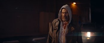 Movie still from “Archenemy” (2020), directed by Adam Egypt Mortimer – A man with blood all over his face and hooded jacket; Medium shot, Low angle
