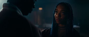 Movie still from “Archenemy” (2020), directed by Adam Egypt Mortimer – A woman with blue braids talking to a man in a dark room; Close Up shot, Over the shoulder angle
