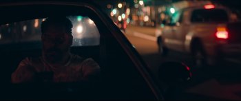 Movie still from “Archenemy” (2020), directed by Adam Egypt Mortimer – A man sitting in the driver's seat of a car at night; Close Up shot, Over the shoulder angle