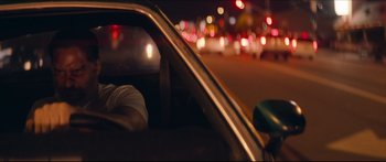 Movie still from “Archenemy” (2020), directed by Adam Egypt Mortimer – A man sitting in a car at night with lights in the background; Close Up shot, Over the shoulder angle