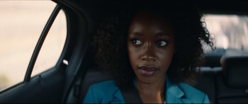 Movie still from “Archenemy” (2020), directed by Adam Egypt Mortimer – A woman sitting in the back seat of a car; Close Up shot, Over the shoulder angle