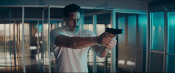 Movie still from “Archenemy” (2020), directed by Adam Egypt Mortimer – A man is holding a gun in a room; Medium shot, Low angle