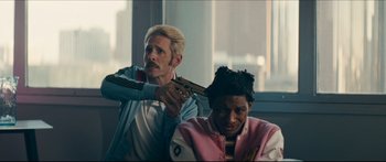 Movie still from “Archenemy” (2020), directed by Adam Egypt Mortimer – A man is holding a gun up to a woman's head; Medium shot, Over the shoulder angle