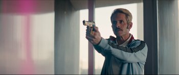 Movie still from “Archenemy” (2020), directed by Adam Egypt Mortimer – A man holding a gun in a room; Close Up shot, Low angle