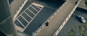 Movie still from “Archenemy” (2020), directed by Adam Egypt Mortimer – An aerial view of a person skateboarding on a sidewalk; Extreme Wide shot, Overhead angle