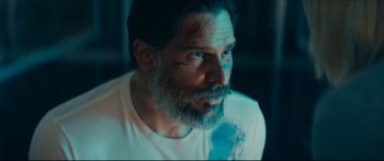 Movie still from “Archenemy” (2020), directed by Adam Egypt Mortimer – A man with a beard and a white t - shirt; Close Up shot, Over the shoulder angle