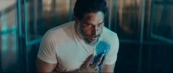 Movie still from “Archenemy” (2020), directed by Adam Egypt Mortimer – A man with a beard holding something in his hand; Medium shot, Over the shoulder angle