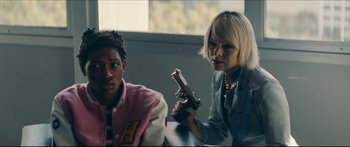 Movie still from “Archenemy” (2020), directed by Adam Egypt Mortimer – A woman holding a gun next to a young man; Medium shot, Over the shoulder angle