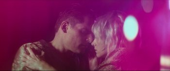 Movie still from “Archenemy” (2020), directed by Adam Egypt Mortimer – A man and a woman face to face in front of a purple background; Close Up shot, Low angle