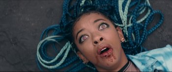 Movie still from “Archenemy” (2020), directed by Adam Egypt Mortimer – A woman with blue hair is laying on the ground with her mouth open; Close Up shot, Overhead angle