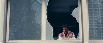 Movie still from “Archenemy” (2020), directed by Adam Egypt Mortimer – A man sitting on top of a window sill; Medium shot, Over the shoulder angle