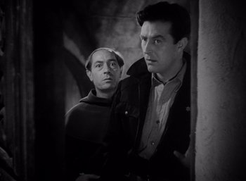 Movie still from “Arise, My Love” (1940), directed by Mitchell Leisen – Two men standing next to each other near a wall; Medium shot, Low angle
