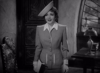 Movie still from “Arise, My Love” (1940), directed by Mitchell Leisen – A black and white photo of a woman in a suit and hat; Medium shot, Low angle