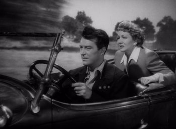 Movie still from “Arise, My Love” (1940), directed by Mitchell Leisen – A man and a woman driving a car in a field; Medium shot, Low angle