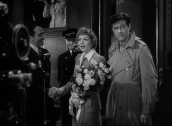 Movie still from “Arise, My Love” (1940), directed by Mitchell Leisen – A man and a woman holding a bouquet of flowers; Medium shot, Over the shoulder angle
