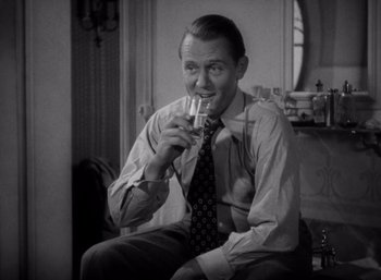 Movie still from “Arise, My Love” (1940), directed by Mitchell Leisen – A black and white photo of a man drinking a glass of wine; Medium shot, High angle