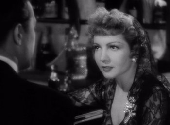 Movie still from “Arise, My Love” (1940), directed by Mitchell Leisen – An old black and white photo of a woman sitting at a table; Close Up shot, Over the shoulder angle