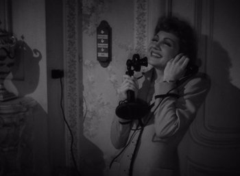 Movie still from “Arise, My Love” (1940), directed by Mitchell Leisen – An old photo of a woman talking on a phone; Medium shot, High angle