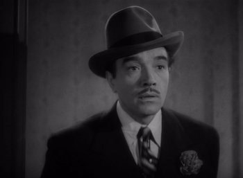 Movie still from “Arise, My Love” (1940), directed by Mitchell Leisen – A man wearing a suit and a hat in a black and white photo; Close Up shot, High angle