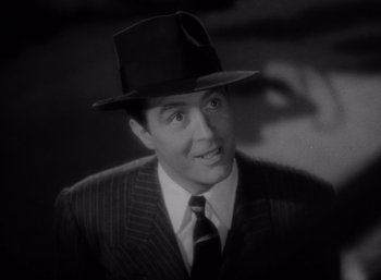 Movie still from “Arise, My Love” (1940), directed by Mitchell Leisen – A black and white photo of a man in a suit and hat; Close Up shot, Low angle