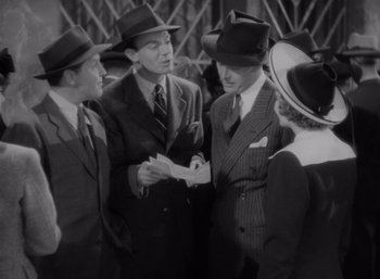Movie still from “Arise, My Love” (1940), directed by Mitchell Leisen – A black and white photo of a group of men talking; Medium shot, High angle