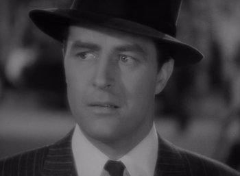 Movie still from “Arise, My Love” (1940), directed by Mitchell Leisen – A black and white photo of a man in a suit and a hat; Close Up shot, Over the shoulder angle