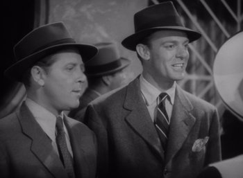 Movie still from “Arise, My Love” (1940), directed by Mitchell Leisen – A black and white photo of two men in suits and hats; Medium shot, Low angle