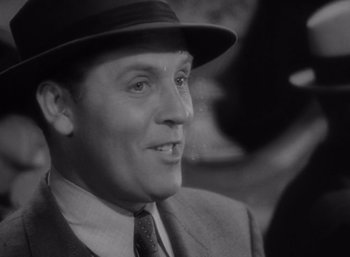 Movie still from “Arise, My Love” (1940), directed by Mitchell Leisen – A man wearing a suit and a hat is smiling; Close Up shot, Over the shoulder angle