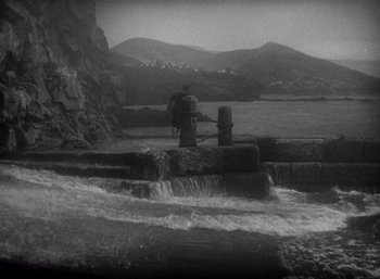 Movie still from “Arise, My Love” (1940), directed by Mitchell Leisen – A man standing next to a river with a mountain in the background; Extreme Wide shot, High angle