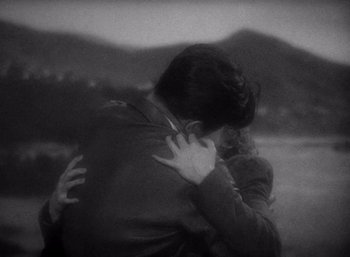 Movie still from “Arise, My Love” (1940), directed by Mitchell Leisen – A man and a woman hugging each other in front of mountains; Medium shot, High angle