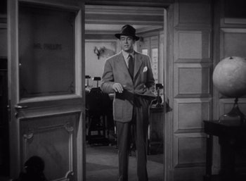 Movie still from “Arise, My Love” (1940), directed by Mitchell Leisen – A black and white photo of a man in a suit and hat; Medium shot, High angle