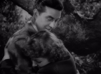 Movie still from “Arise, My Love” (1940), directed by Mitchell Leisen – A man and a woman hugging each other in a forest; Medium shot, High angle