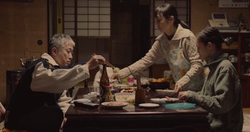 Two people at a table with food and chopsticks