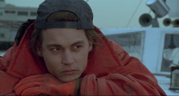 Movie still from “Arizona Dream” (1993), directed by Emir Kusturica – A young man wearing a red jacket and a hat; Close Up shot, Over the shoulder angle
