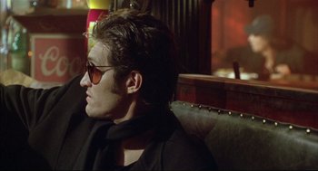 Movie still from “Arizona Dream” (1993), directed by Emir Kusturica – A man sitting on a couch wearing sunglasses; Close Up shot, Low angle