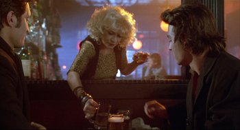 Movie still from “Arizona Dream” (1993), directed by Emir Kusturica – A woman is pouring a drink into a glass; Medium shot, Over the shoulder angle