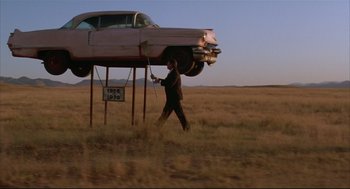 Movie still from “Arizona Dream” (1993), directed by Emir Kusturica – A man in a field next to an old pink car; Wide shot, Low angle