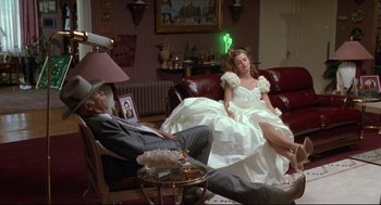 Movie still from “Arizona Dream” (1993), directed by Emir Kusturica – A man and a woman sitting on a couch in a living room next to each other; Wide shot, High angle