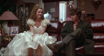 Movie still from “Arizona Dream” (1993), directed by Emir Kusturica – A man and a woman sitting on a couch in front of a window; Medium shot, Low angle