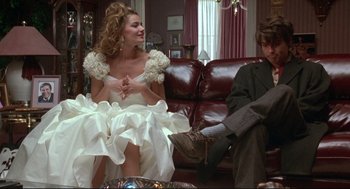 Movie still from “Arizona Dream” (1993), directed by Emir Kusturica – A woman in a white dress sitting next to a man in a suit; Medium shot, Low angle
