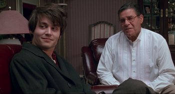 Movie still from “Arizona Dream” (1993), directed by Emir Kusturica – A man and a man sitting next to each other in a room; Medium shot, Over the shoulder angle