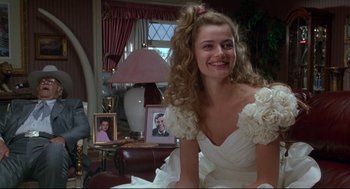 Movie still from “Arizona Dream” (1993), directed by Emir Kusturica – A woman in a white wedding dress sitting in a living room; Medium shot, Over the shoulder angle